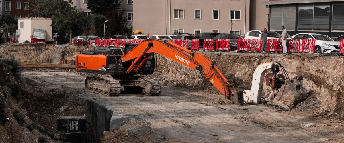 Excavators operating at an urban construction site surrounded by residential buildings