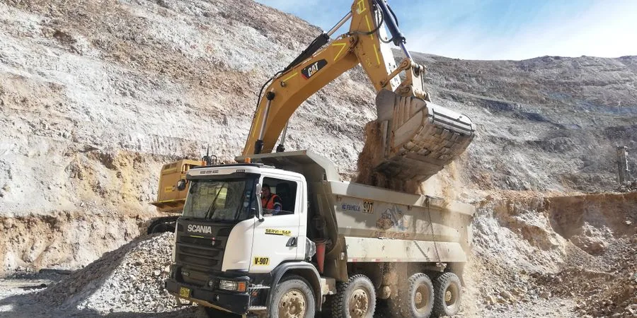 Excavator loading a dump truck in a quarry — industrial material handling that illustrates the dump cycle small dumper trucks perform on a smaller scale for confined site access