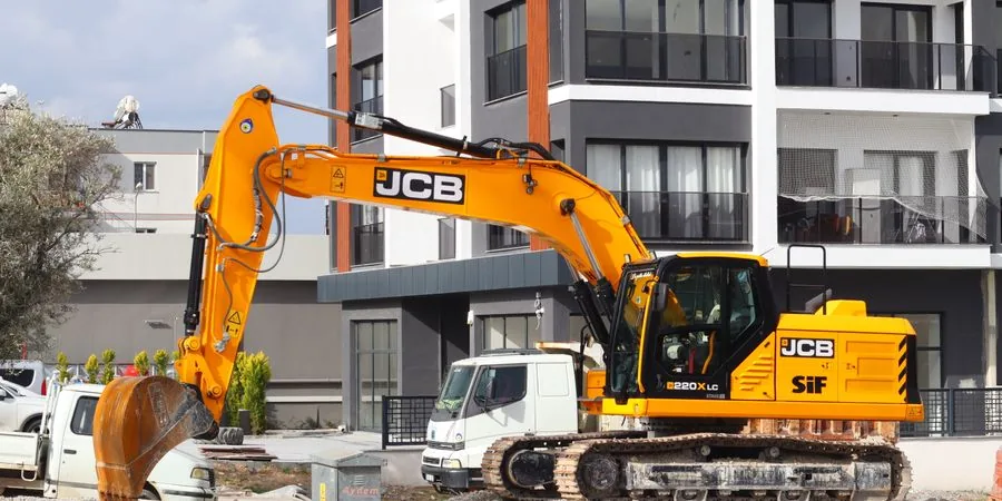 Yellow excavator operating at a city construction site in front of modern buildings