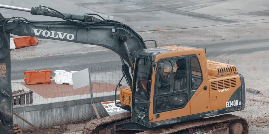 Yellow excavator with rubber tracks on a muddy construction site — showing how tracked machines maintain traction on soft, wet ground